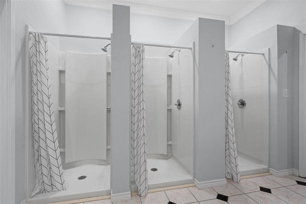 Full bathroom with a shower stall, light tile patterned floors, and crown molding