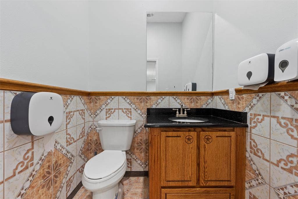 Bathroom featuring tile walls, wainscoting, and vanity