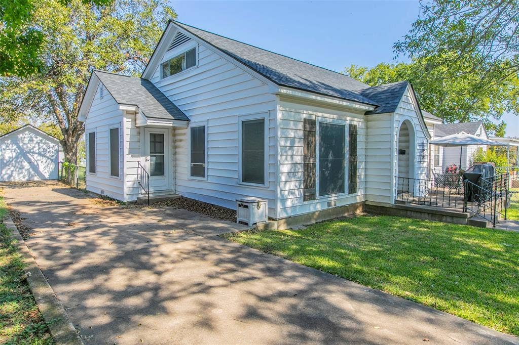 2603 Pine Avenue, Waco, TX 76708 View of front of house featuring roof with shingles, an outdoor structure, a detached garage, driveway, and a front lawn