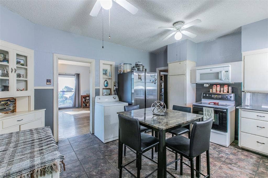 2603 Pine Avenue, Waco, TX 76708 Kitchen with electric range oven, washer / clothes dryer, white cabinets, a textured ceiling, and white microwave