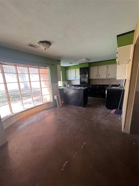 4038 State Highway 351, Abilene, TX 79601 Kitchen with concrete floors, a textured ceiling, oven, dark cabinets, and a peninsula