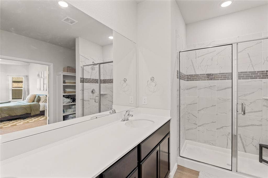 Ensuite bathroom with a marble finish shower, vanity, recessed lighting, and light wood-type flooring