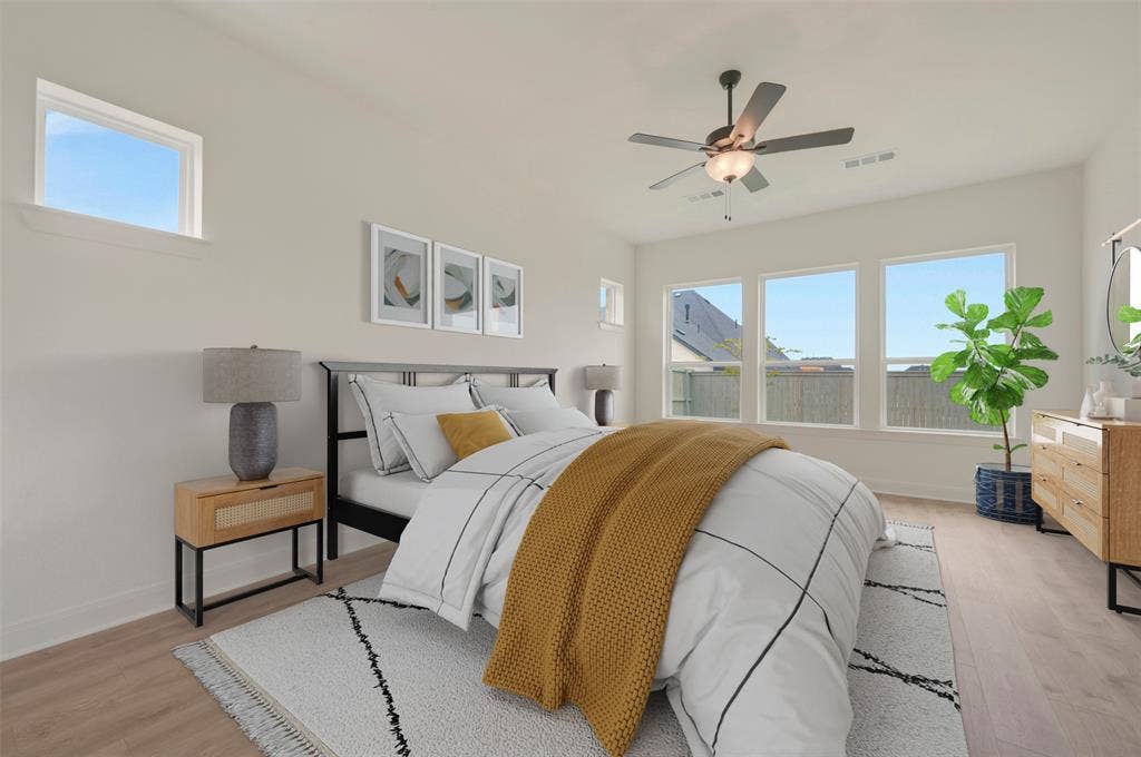 Light-filled bedroom featuring wood-finish flooring, a ceiling fan, and multiple windows