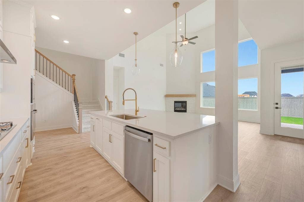 Open-concept kitchen featuring a large island with sink, white cabinetry, and stainless steel appliances