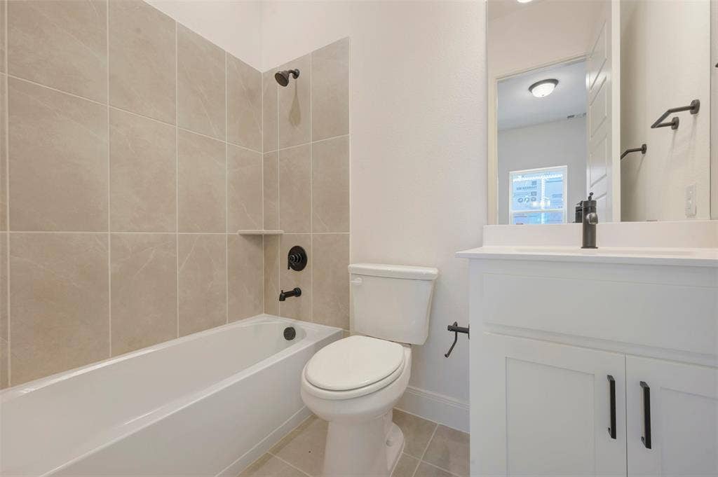 Bathroom featuring a white bathtub, light-toned tile surround with a built-in niche, and matte black plumbing fixtures
