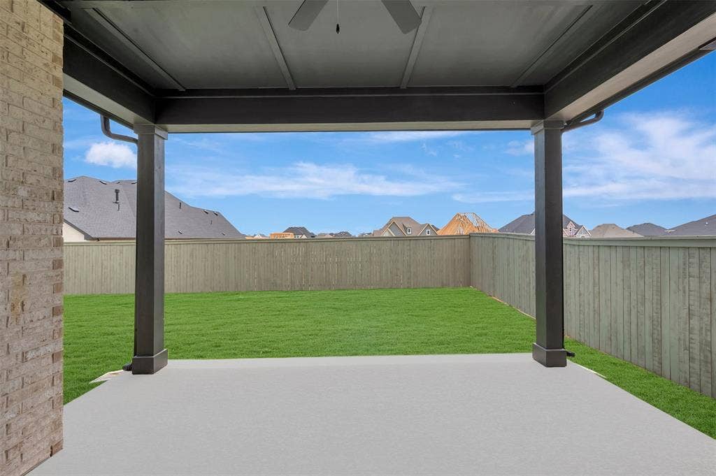 Covered concrete patio with ceiling fan, brick exterior accent, fenced backyard, and manicured lawn
