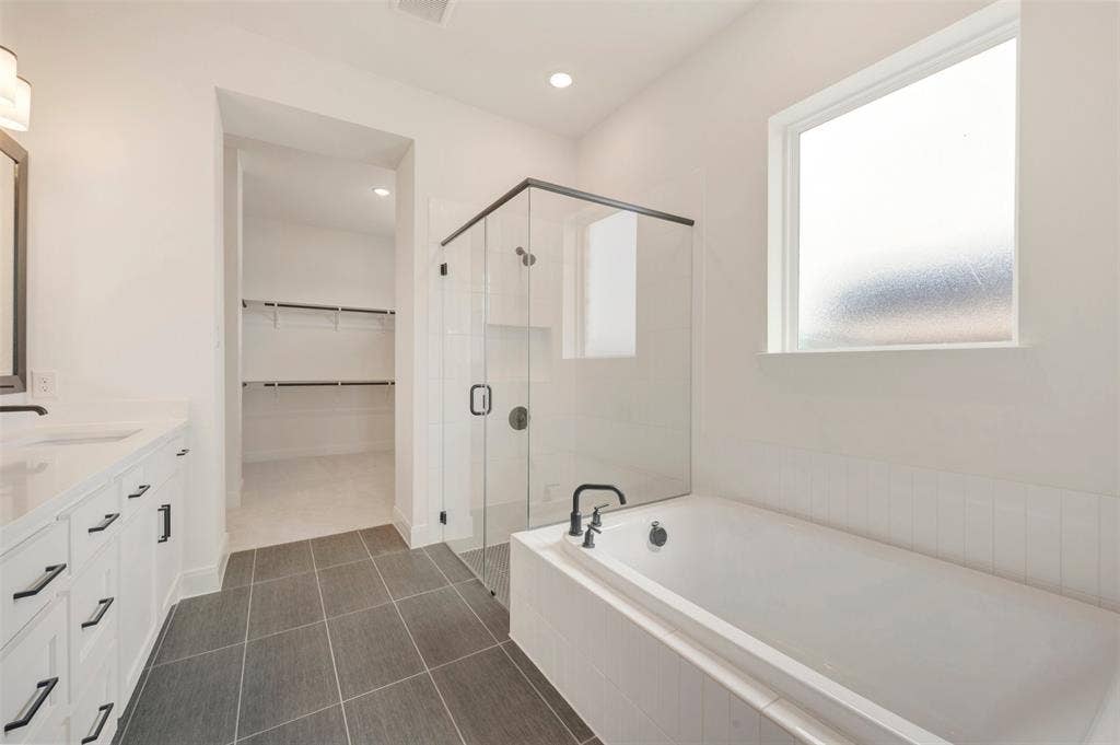 Modern bath featuring a frameless glass shower enclosure, a built-in soaking tub, and a vanity with dual sinks