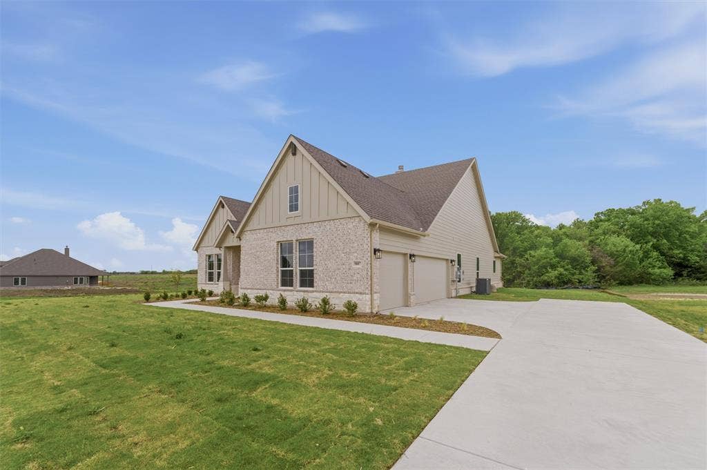 9007 County Road 623, Blue Ridge, TX 75424 View of property exterior with board and batten siding, brick siding, a lawn, and concrete driveway