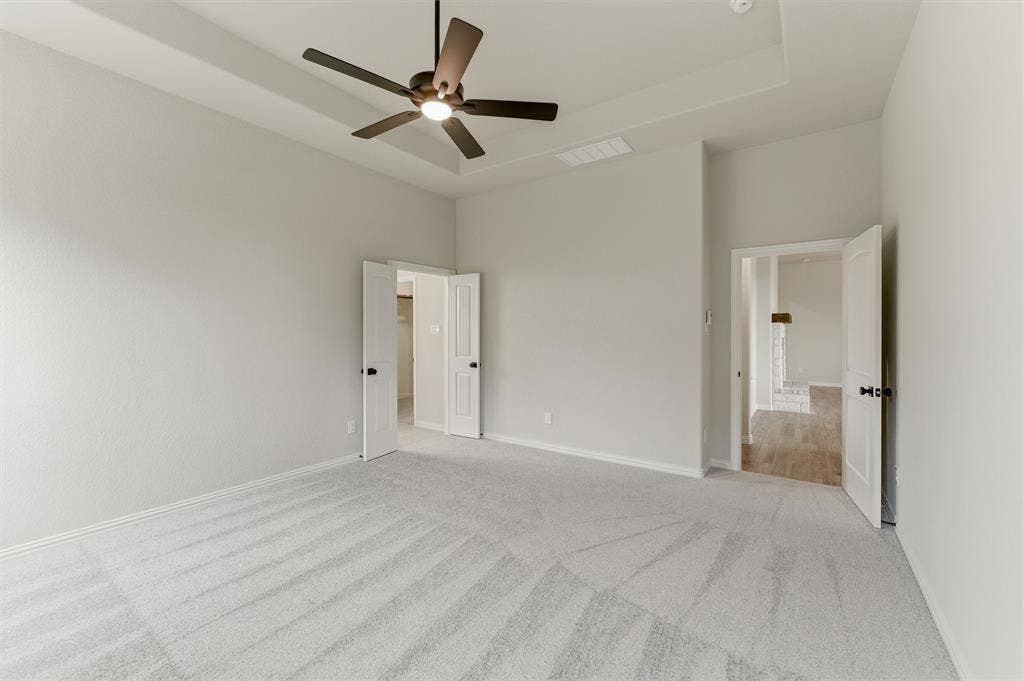 9007 County Road 623, Blue Ridge, TX 75424 Unfurnished bedroom featuring a tray ceiling, a ceiling fan, light carpet, and ensuite bathroom