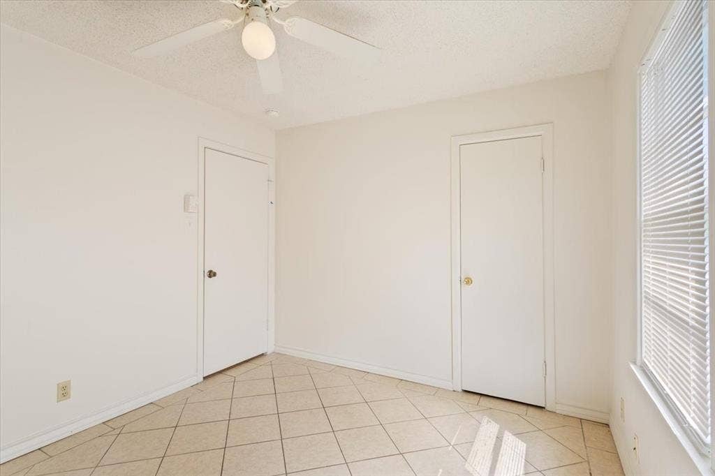 2424 S 26th Street, Waco, TX 76706 Unfurnished bedroom with a ceiling fan, light tile patterned flooring, and a textured ceiling
