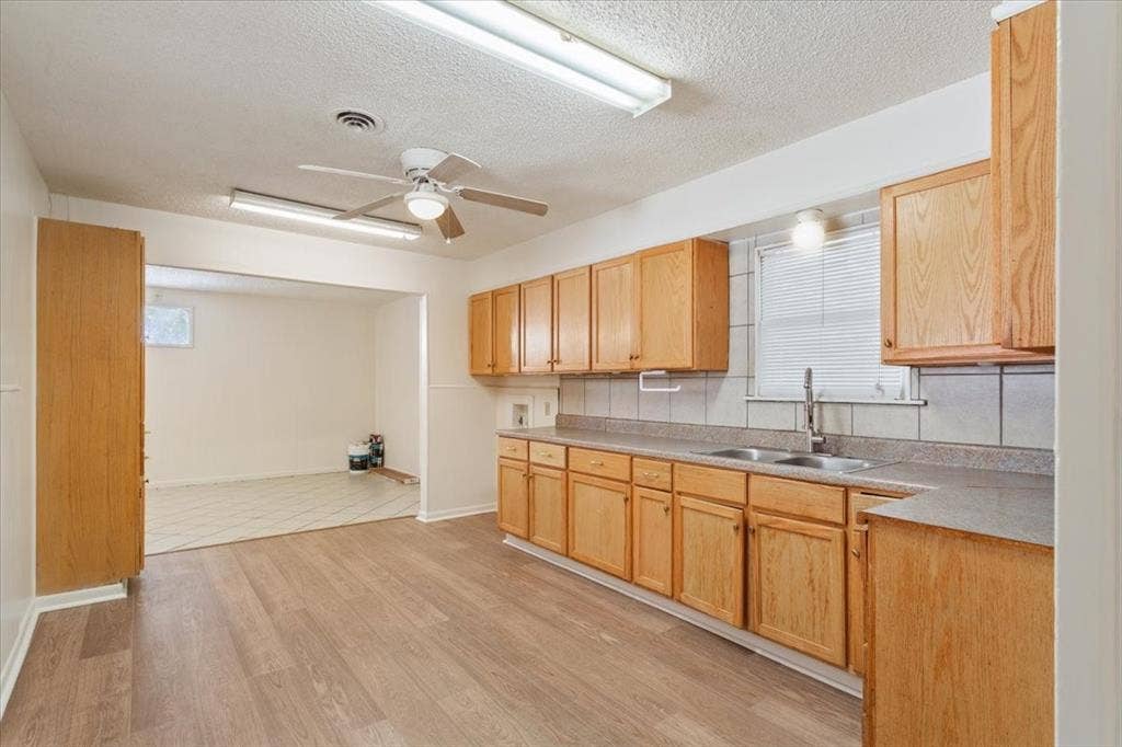 2424 S 26th Street, Waco, TX 76706 Kitchen featuring light countertops, a textured ceiling, a ceiling fan, light brown cabinetry, and light wood-type flooring