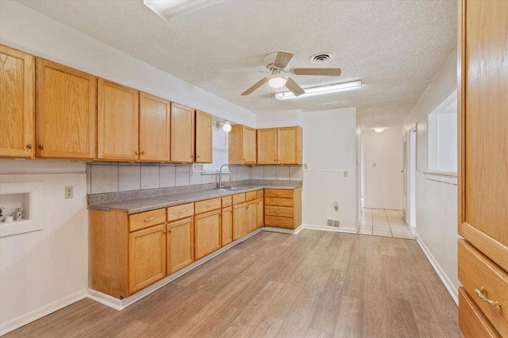 2424 S 26th Street, Waco, TX 76706 Kitchen featuring light wood-style floors, light brown cabinets, a ceiling fan, light countertops, and a textured ceiling
