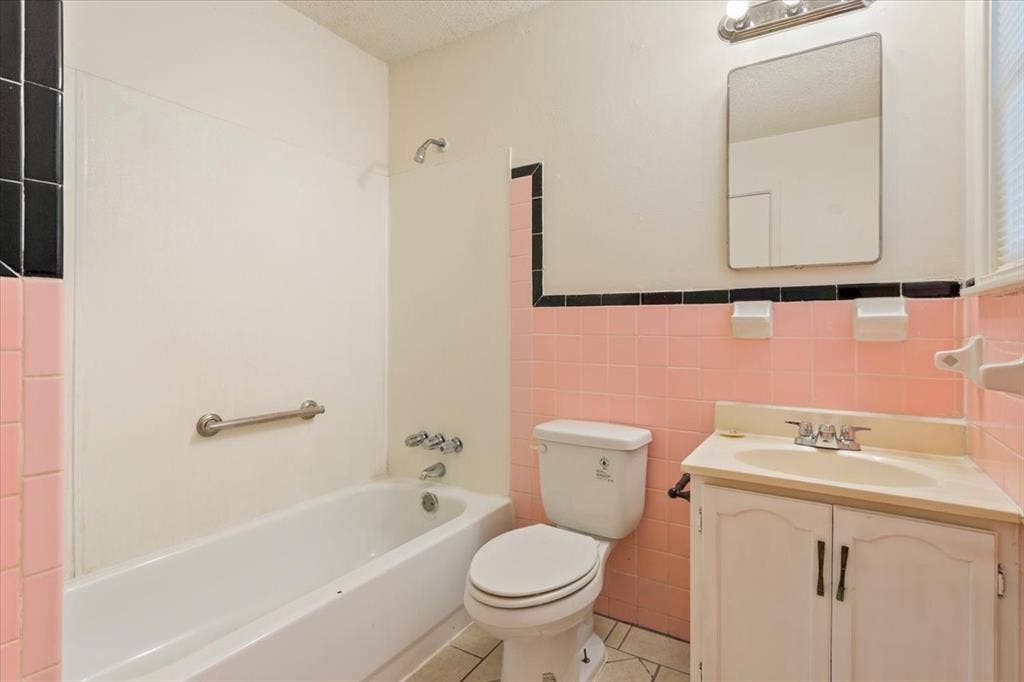 2424 S 26th Street, Waco, TX 76706 Bathroom with tile walls, vanity, light tile patterned flooring, washtub / shower combination, and a textured ceiling