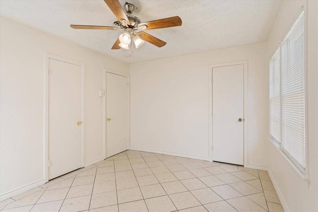 2424 S 26th Street, Waco, TX 76706 Unfurnished bedroom with light tile patterned floors and a ceiling fan