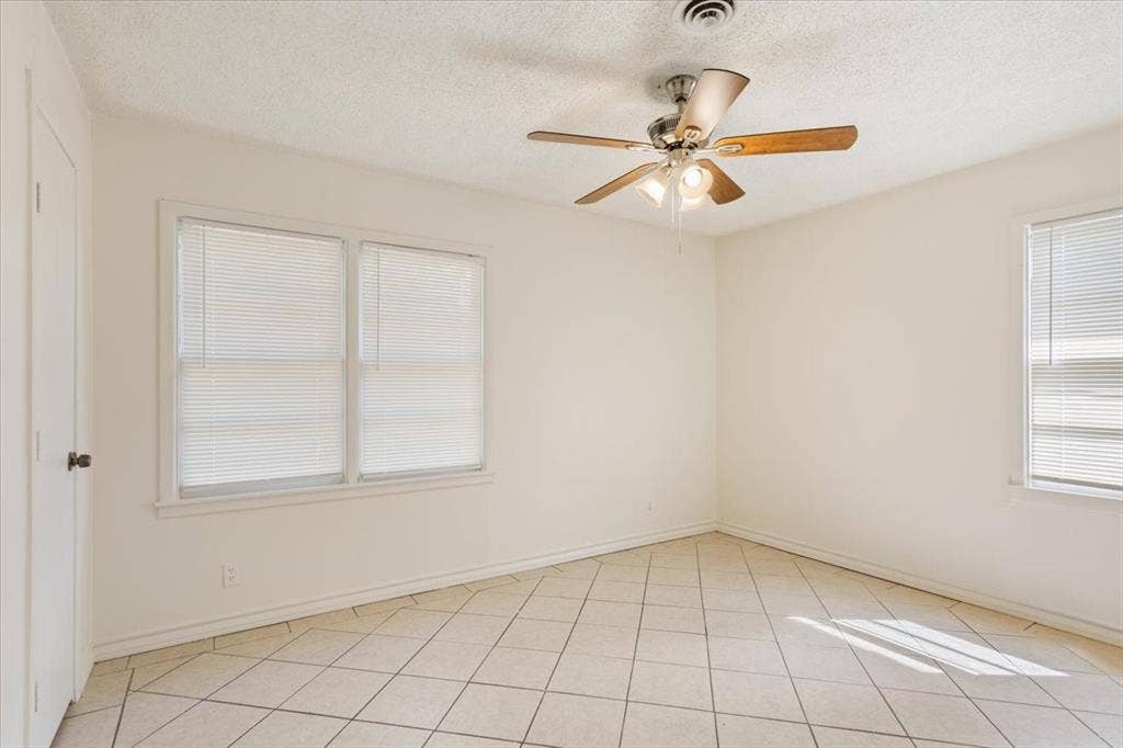 2424 S 26th Street, Waco, TX 76706 Spare room with a textured ceiling, light tile patterned floors, healthy amount of natural light, and a ceiling fan