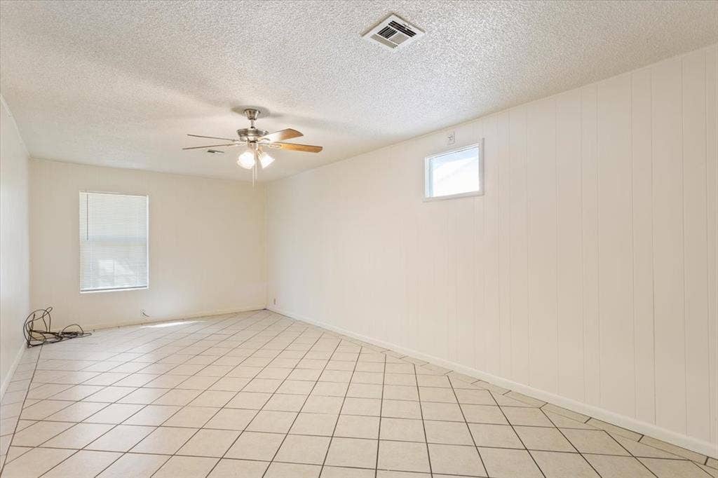 2424 S 26th Street, Waco, TX 76706 Empty room with a textured ceiling, ceiling fan, and light tile patterned floors