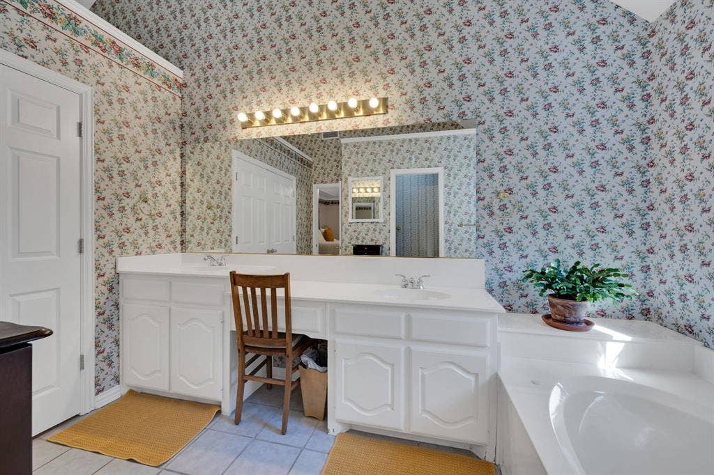 Bathroom with double vanity, light tile patterned flooring, and a garden tub