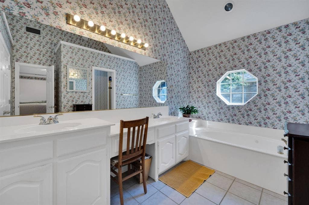 Bathroom with double vanity, light tile patterned floors, a garden tub, and wallpapered walls