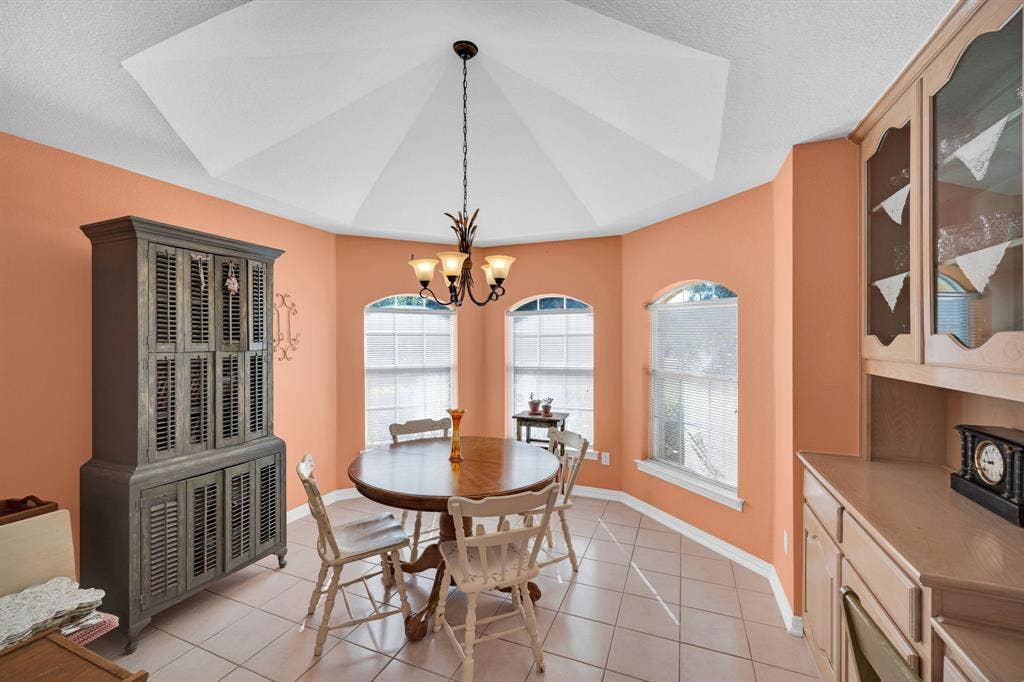 Dining room with light tile patterned flooring, a chandelier, and a textured ceiling