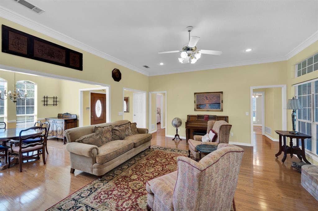 Living area featuring crown molding, wood finished floors, a chandelier, a ceiling fan, and recessed lighting