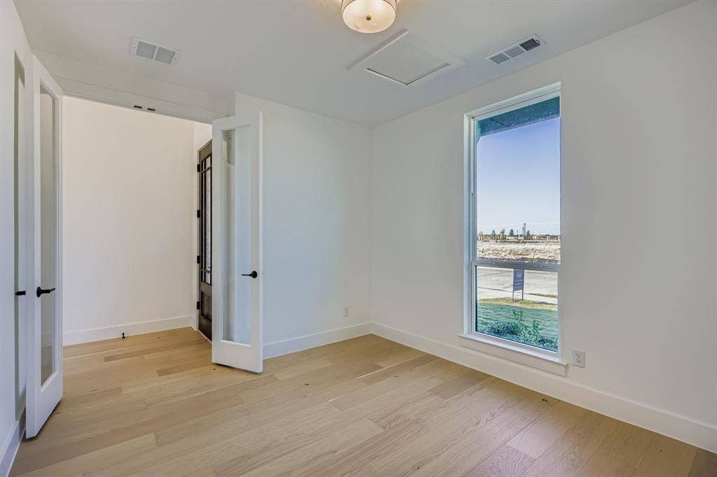 Unfurnished bedroom featuring light wood finished floors and attic access