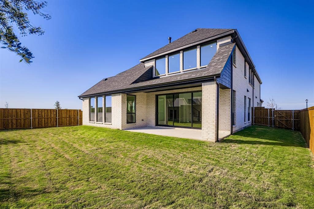 Back of house with brick siding, roof with shingles, a patio, and a fenced backyard