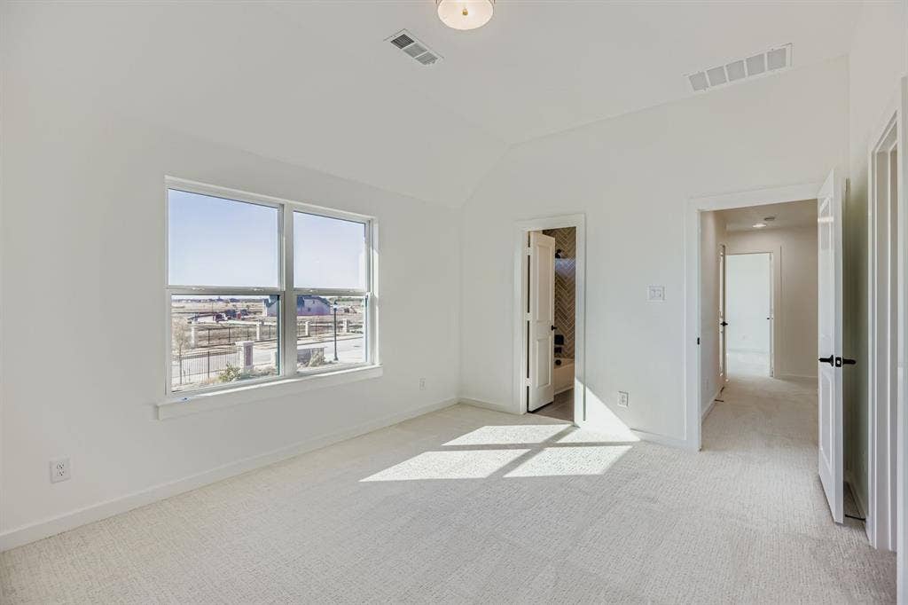 Unfurnished bedroom with light colored carpet and lofted ceiling