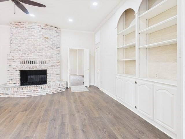 1178 E Oval Drive, Athens, TX 75751 Unfurnished living room featuring dark wood-type flooring, crown molding, a fireplace, a ceiling fan, and recessed lighting