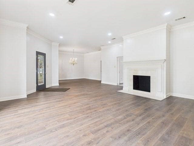 1178 E Oval Drive, Athens, TX 75751 Unfurnished living room featuring wood finished floors, ornamental molding, a fireplace with flush hearth, recessed lighting, and a chandelier
