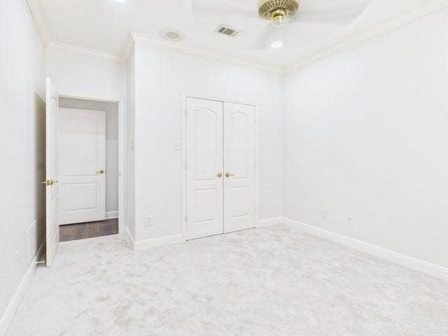 1178 E Oval Drive, Athens, TX 75751 Unfurnished bedroom featuring light colored carpet, crown molding, a closet, and ceiling fan