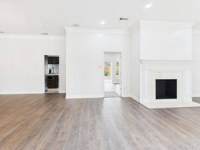 1178 E Oval Drive, Athens, TX 75751 Unfurnished living room featuring ornamental molding, a fireplace with flush hearth, wood finished floors, and recessed lighting