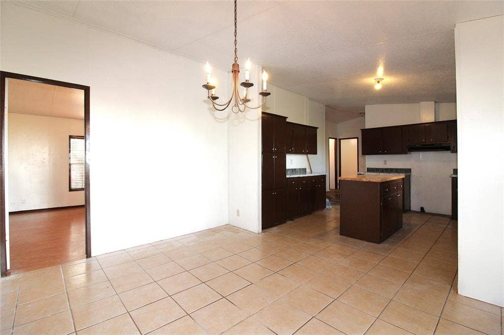 5199 Timarron Drive, Scurry, TX 75158 Kitchen with dark brown cabinets, a chandelier, hanging light fixtures, a center island, and light tile patterned floors