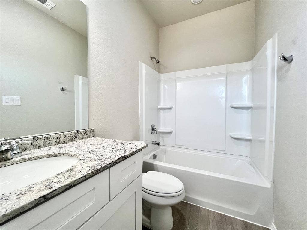3501 E Renfro Street, #106, Burleson, TX 76028 Ensuite bathroom with vanity, bathing tub / shower combination, dark wood-style floors, and a textured wall