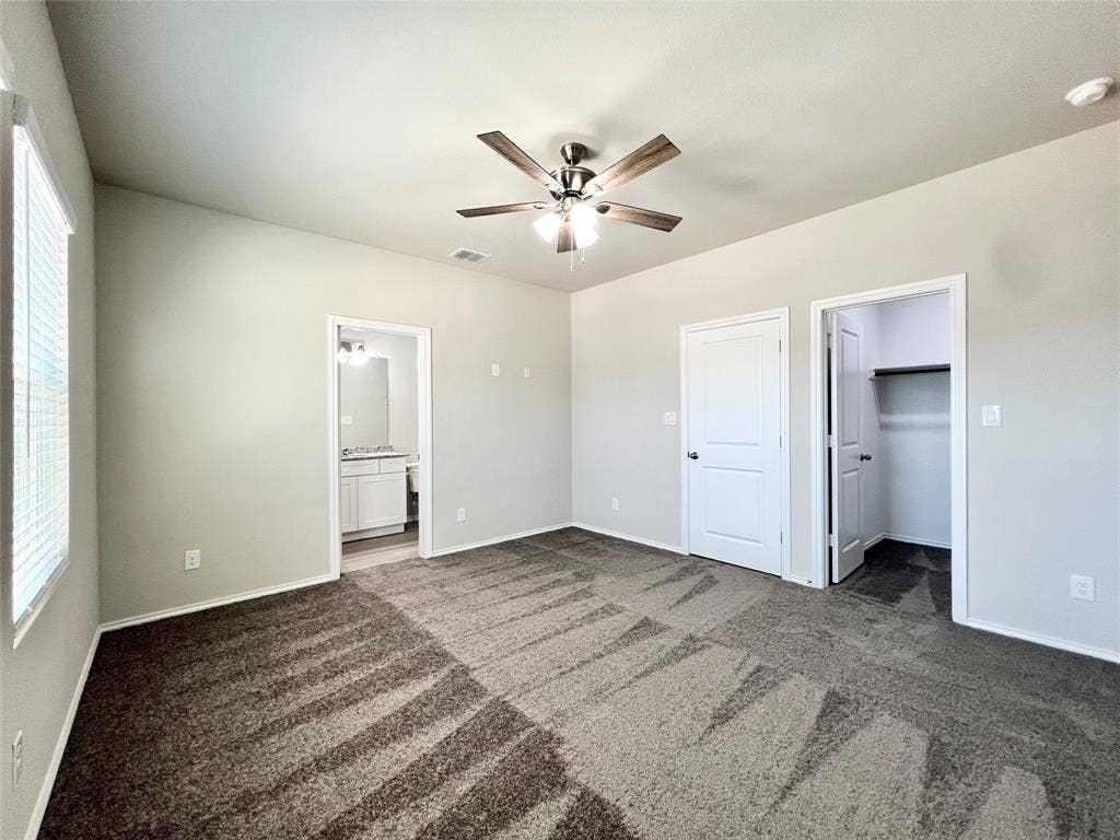 3501 E Renfro Street, #106, Burleson, TX 76028 1st bedroom with dark carpet, a spacious closet, connected bathroom, and a ceiling fan
