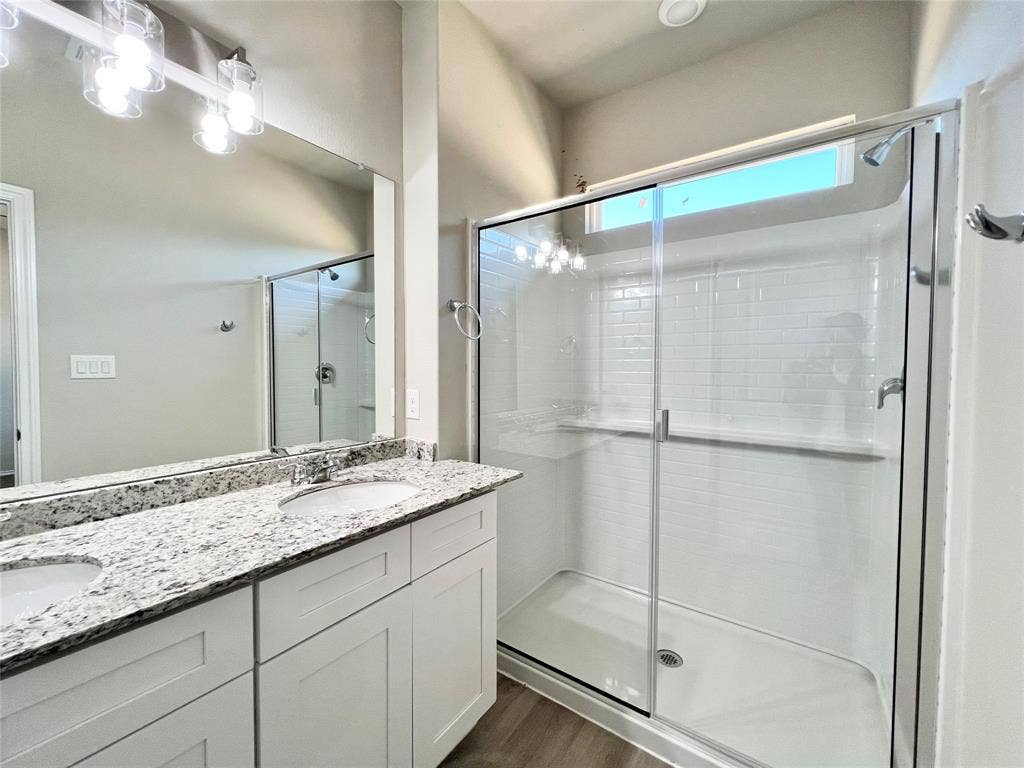 3501 E Renfro Street, #106, Burleson, TX 76028 Primary bathroom featuring double vanity, a shower stall, and dark wood-style floors