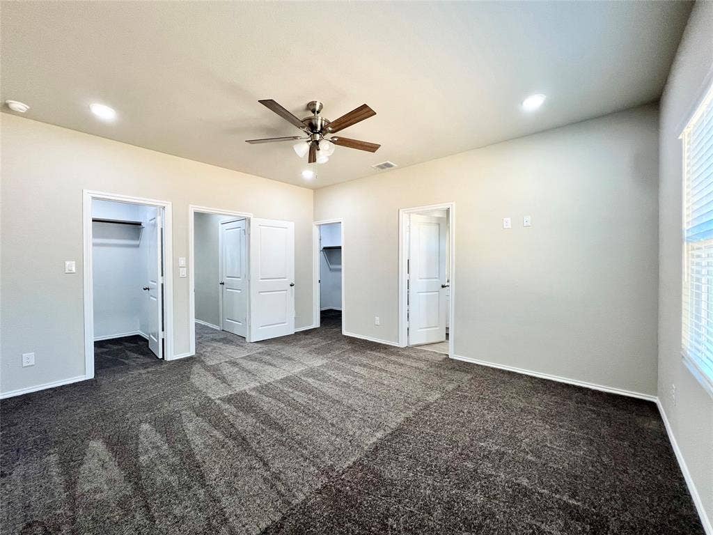 3501 E Renfro Street, #106, Burleson, TX 76028 Primary bedroom featuring a walk in closet, dark carpet, a ceiling fan, and recessed lighting