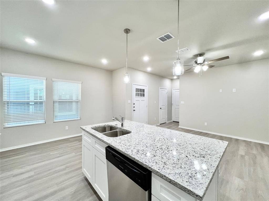 3501 E Renfro Street, #106, Burleson, TX 76028 Kitchen featuring a ceiling fan, white cabinetry, light stone counters, light wood-style flooring, and a center island with sink