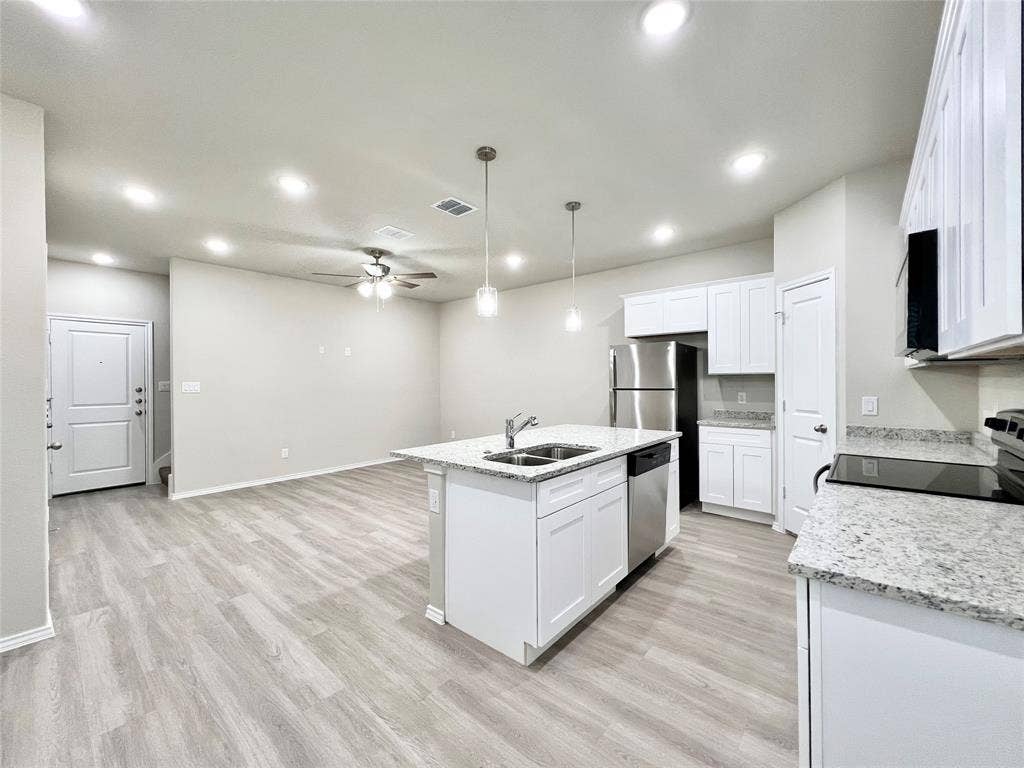 3501 E Renfro Street, #106, Burleson, TX 76028 Kitchen featuring a kitchen island with sink, pendant lighting, ceiling fan, light wood-type flooring, and light stone counters