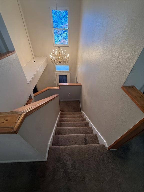 10216 Big Thicket Drive, Dallas, TX 75217 Stairs featuring carpet floors, a textured wall, and a chandelier