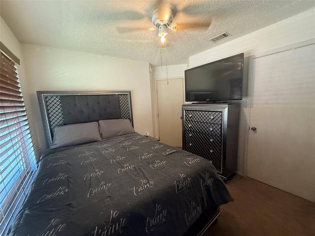10216 Big Thicket Drive, Dallas, TX 75217 Bedroom with a textured ceiling, ceiling fan, and dark colored carpet