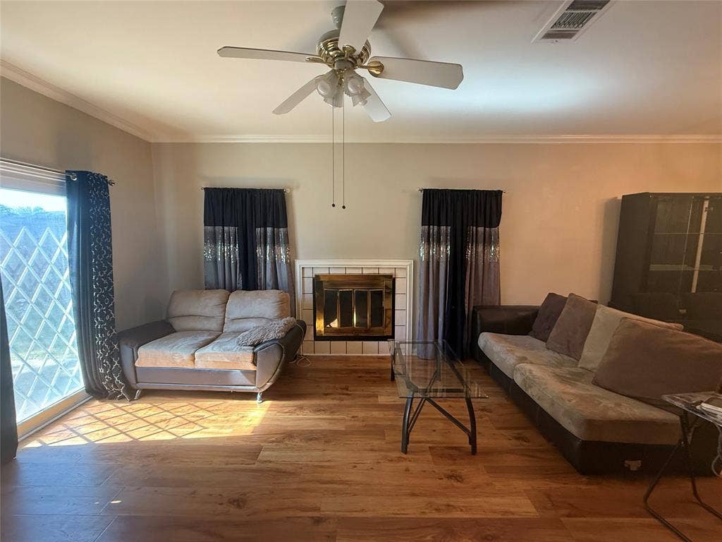 10216 Big Thicket Drive, Dallas, TX 75217 Living room with ornamental molding, a tile fireplace, wood finished floors, and a ceiling fan