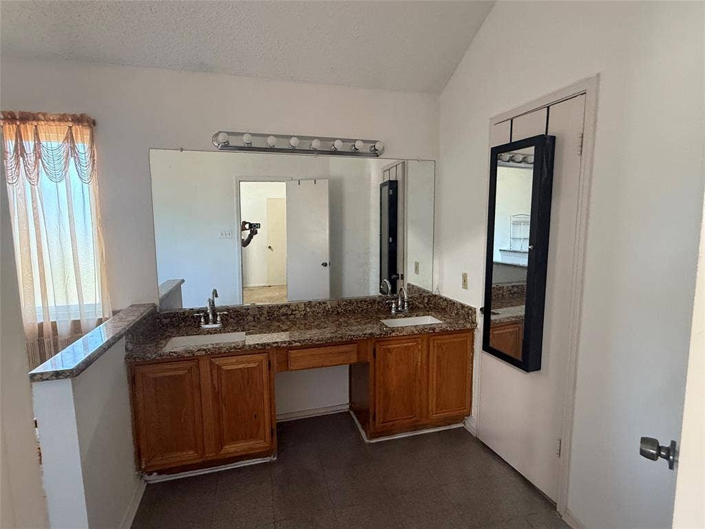 10216 Big Thicket Drive, Dallas, TX 75217 Full bathroom featuring double vanity, a textured ceiling, and lofted ceiling