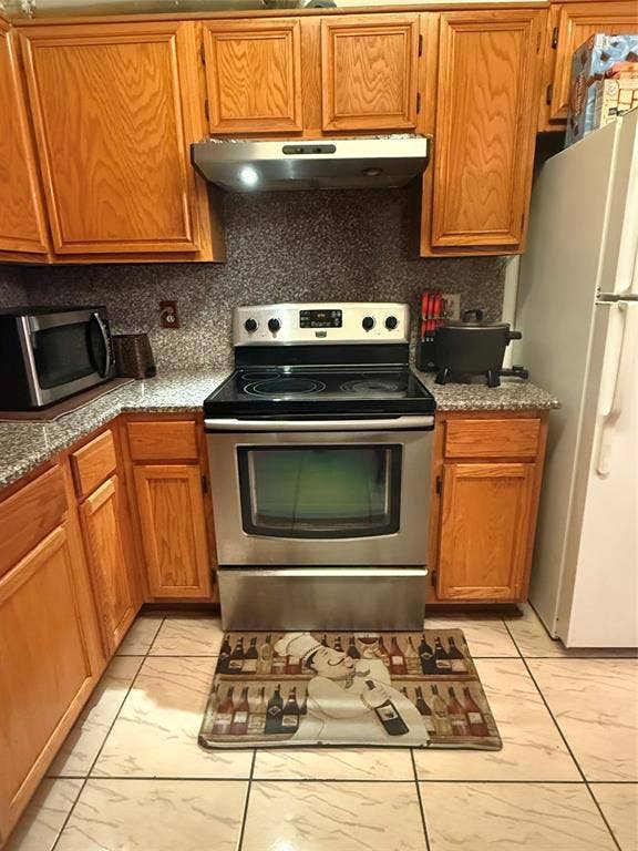 10216 Big Thicket Drive, Dallas, TX 75217 Kitchen featuring stainless steel appliances, tasteful backsplash, brown cabinets, and range hood