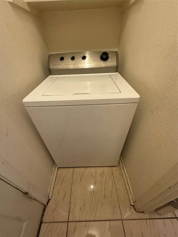 10216 Big Thicket Drive, Dallas, TX 75217 Laundry room with a textured wall, washer / clothes dryer, and marble finish floors