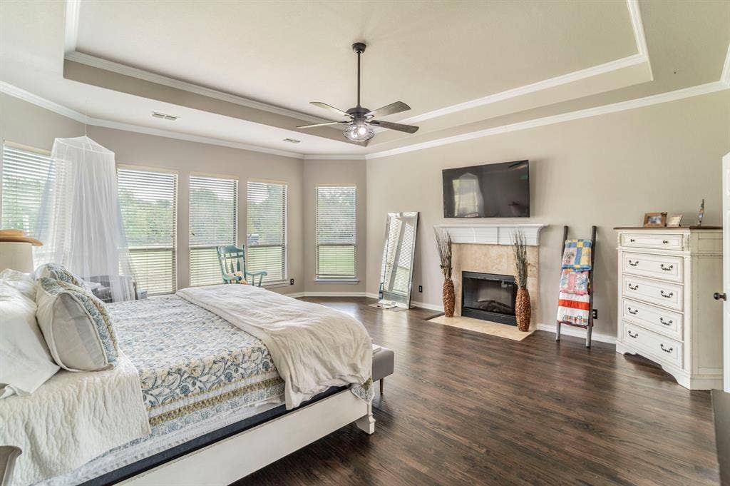 5229 Horseshoe Lane, Royse City, TX 75189 Primary Bedroom with a tray ceiling, a fireplace, dark wood-style floors, crown molding, and a ceiling fan