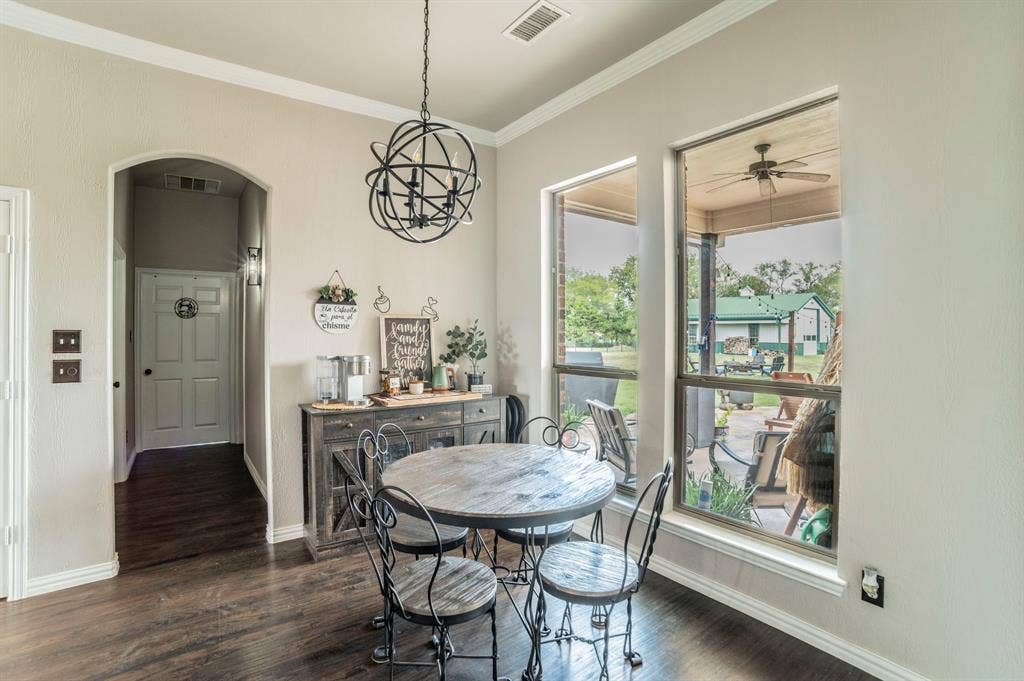 5229 Horseshoe Lane, Royse City, TX 75189 Dining area with ornamental molding, dark wood-style floors, arched walkways all overlooking the patio and back area of the property.