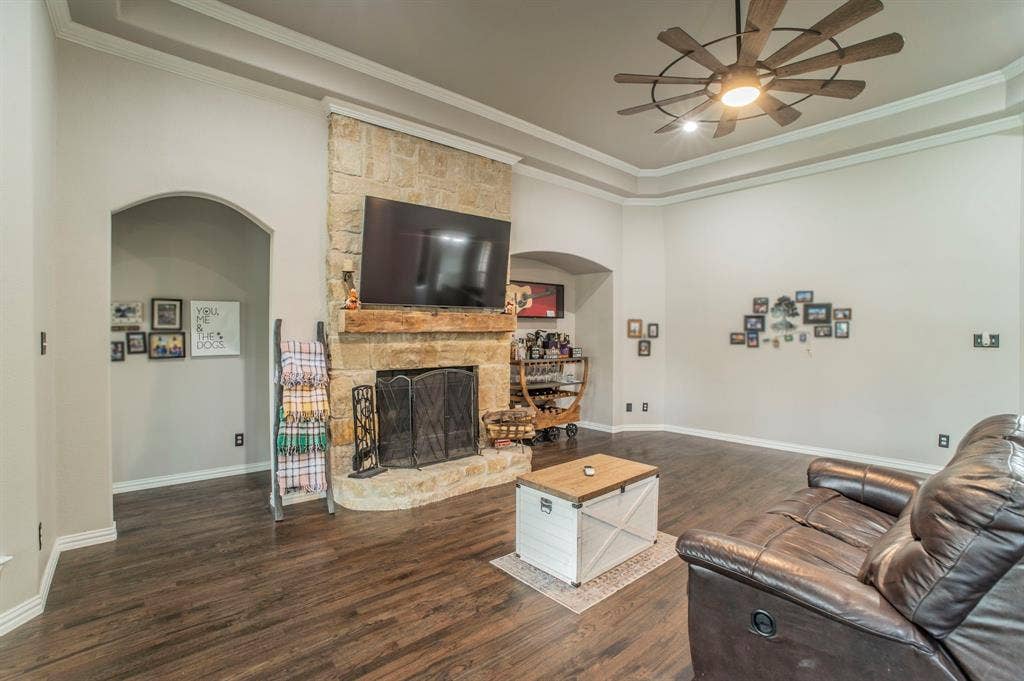5229 Horseshoe Lane, Royse City, TX 75189 Living area with a fireplace, dark wood finished floors, crown molding, arched walkways, and a raised ceiling