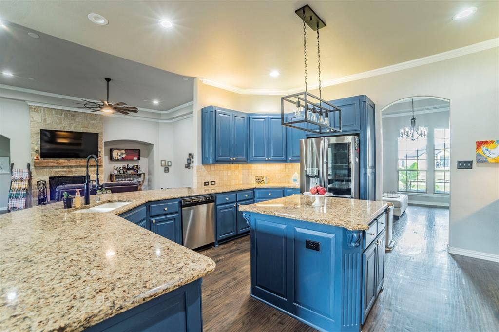 5229 Horseshoe Lane, Royse City, TX 75189 Kitchen featuring arched walkways, blue cabinets, backsplash, crown molding, and open floor plan
