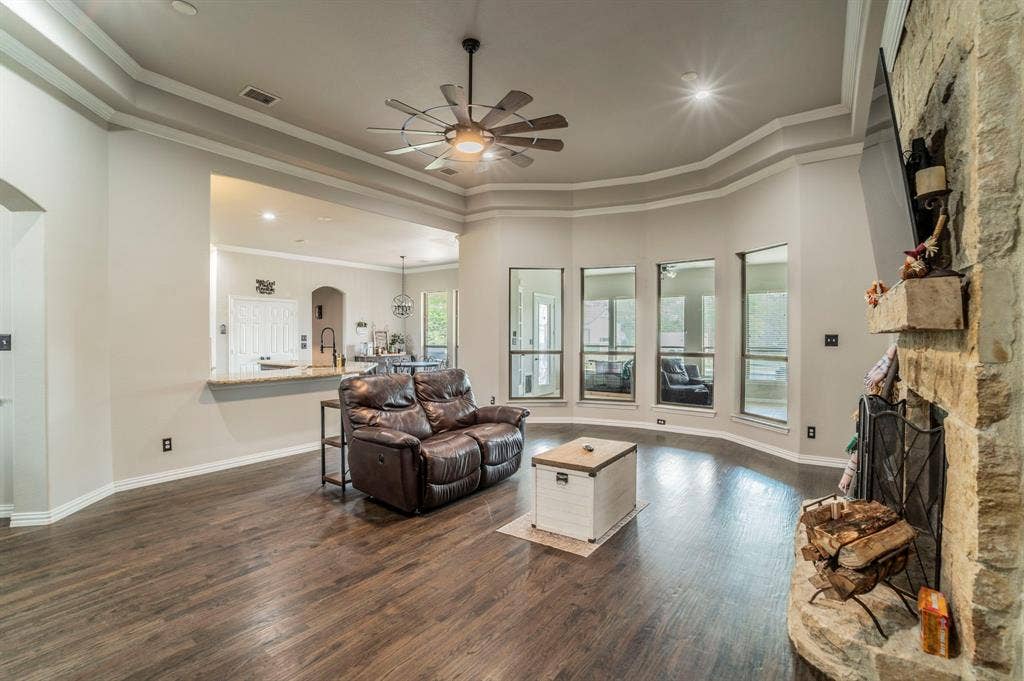 5229 Horseshoe Lane, Royse City, TX 75189 Living area featuring dark wood-style flooring, a ceiling fan, ornamental molding, a fireplace, and arched walkways