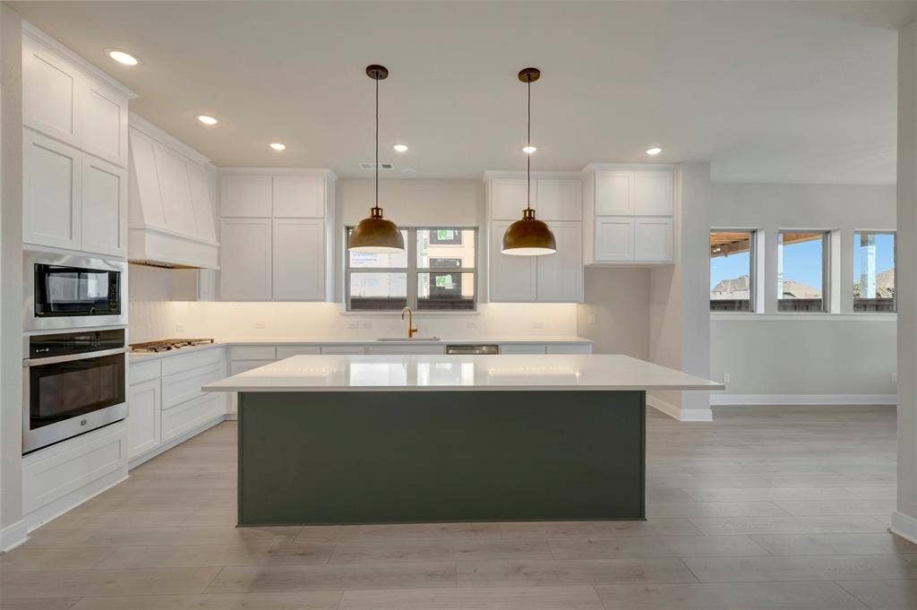 3752 Bermuda Grass Way, Grand Prairie, TX 76084 Dual tone kitchen with a center island, stainless steel appliances, hanging light fixtures, light wood-type flooring, and dual tone cabinets